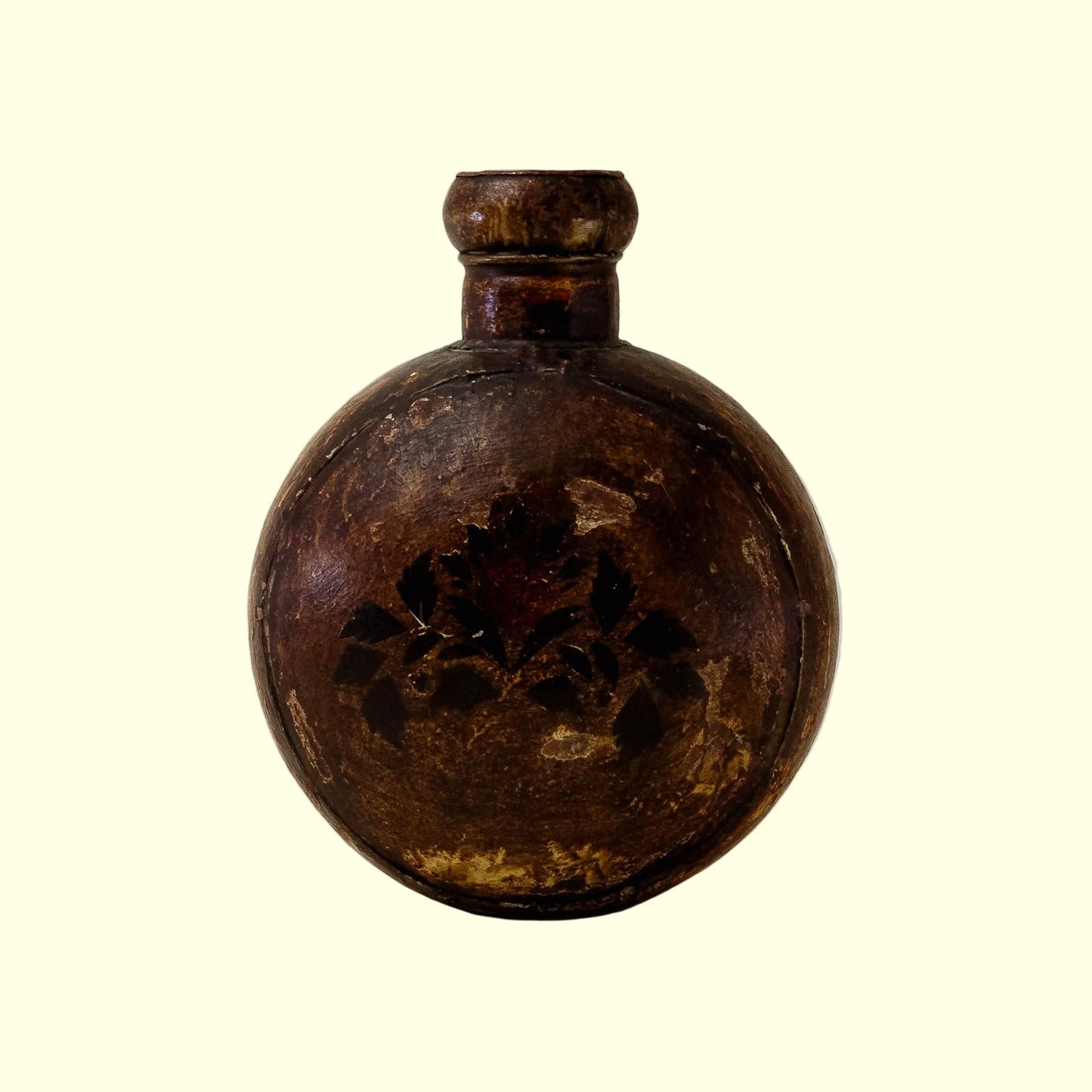 A 19th-century primitive iron and brass oil pot with a floral design on the front and a curved spout, displayed against a neutral background.
