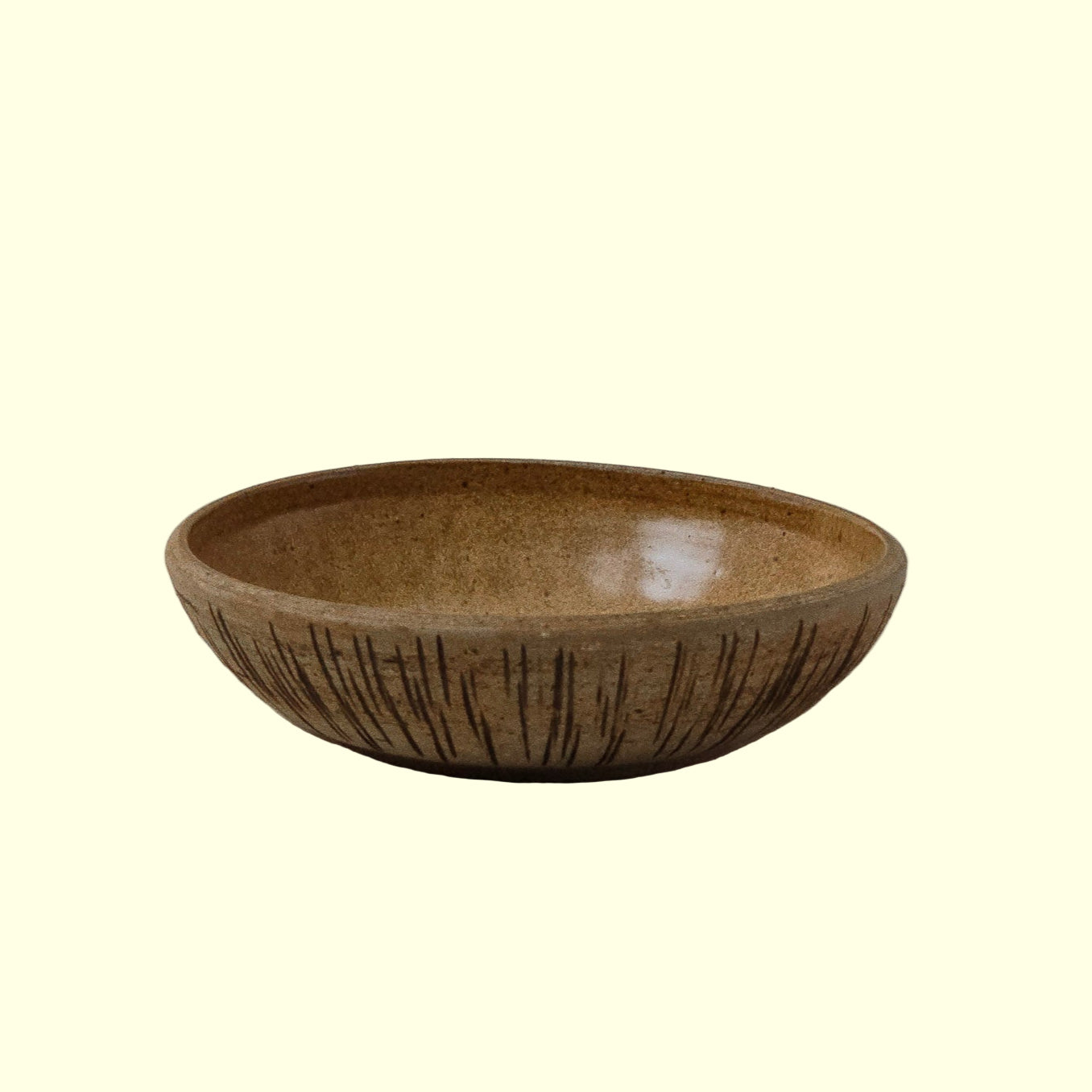 A beige ceramic catch-all bowl with a speckled texture and horizontal stripe detailing on a plain background.