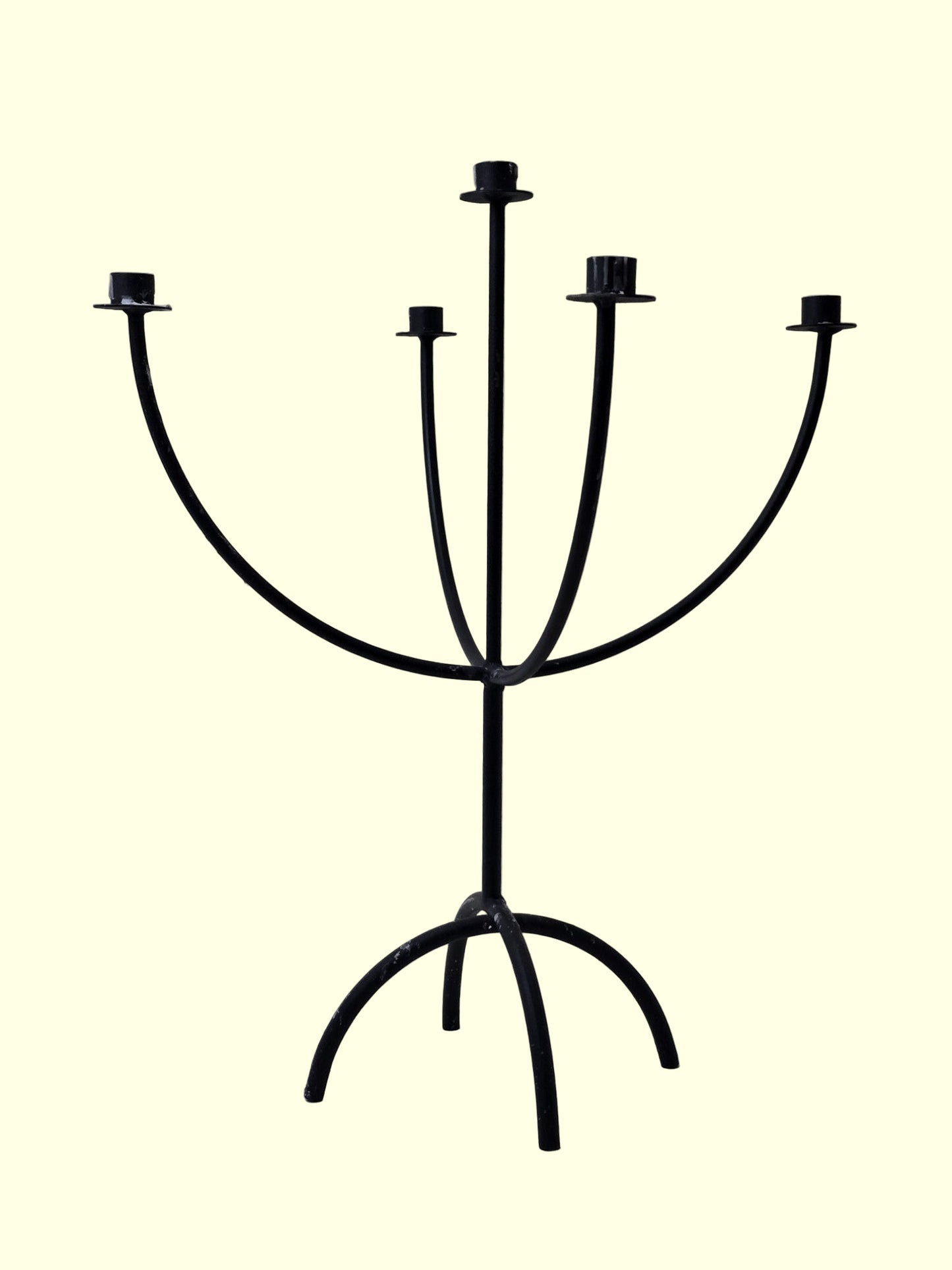 Black metal candelabra with five candle holders on a light gray background