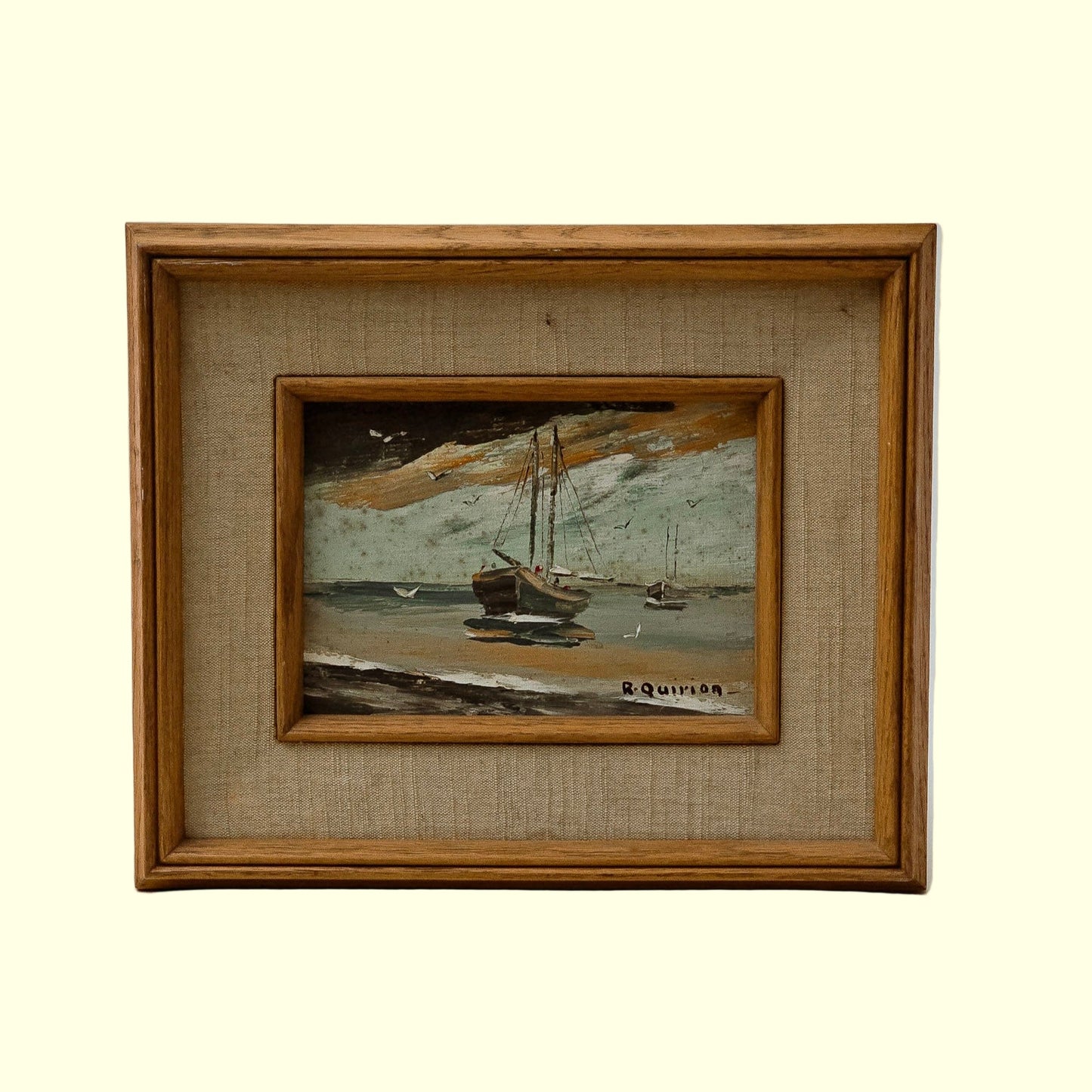 Framed artwork depicting a maritime scene with boats and a lighthouse, signed by the artist, Raymond Quirion.