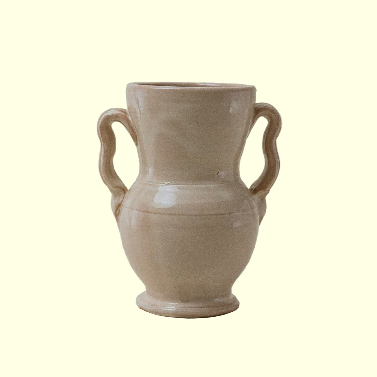 A vintage West German ceramic vase with a cream color and unique squiggly handles.