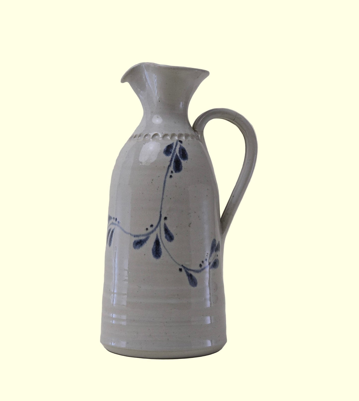 Ceramic pitcher with blue floral design on a plain background