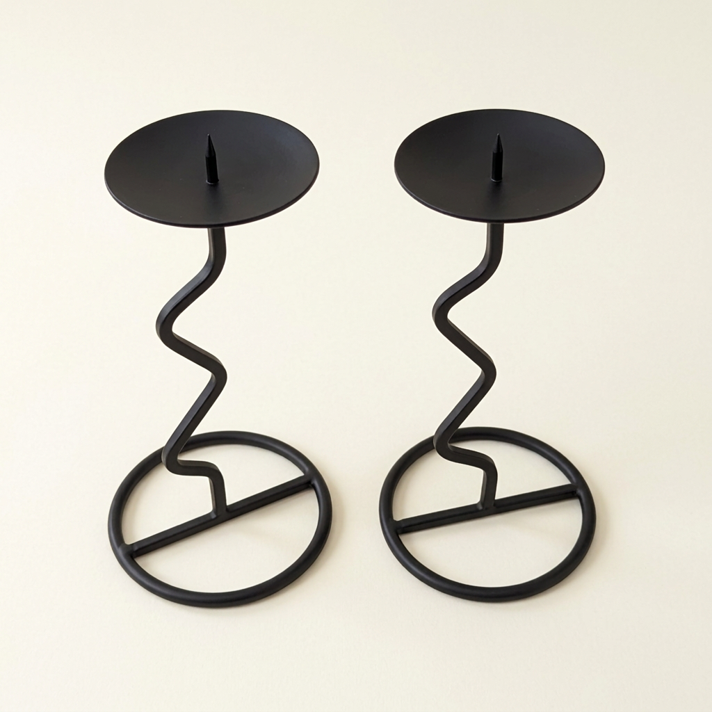 A pair of black metal candle holders with circular plates and twisted spiral supports, set against a solid beige background.