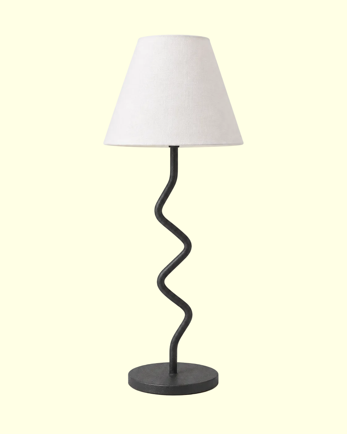 A table lamp with a tapered off-white fabric shade and a twisted black metal base on a light cream background.