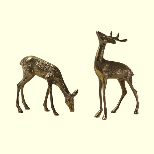 Two bronze deer figurines on a light beige background
